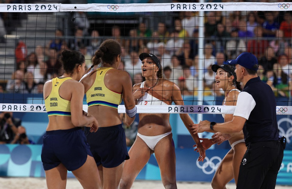 a group of women playing volleyball in front of a net that says paris 2024