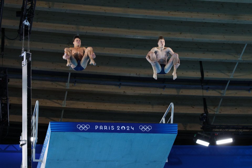 two men are jumping off a diving board that says paris 2024