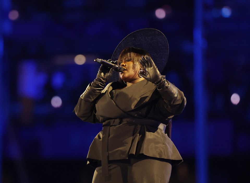 a woman wearing a hat and gloves sings into a microphone