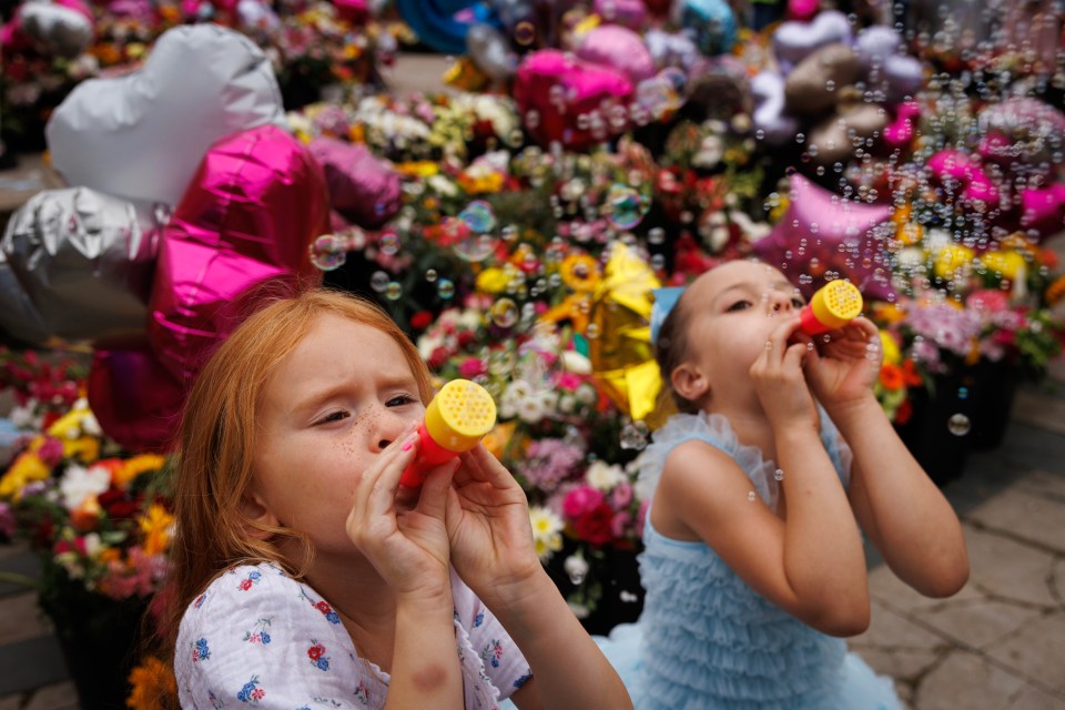 School friends blow bubbles as people gather to mourn