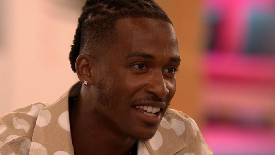 a close up of a man wearing earrings and a polka dot shirt