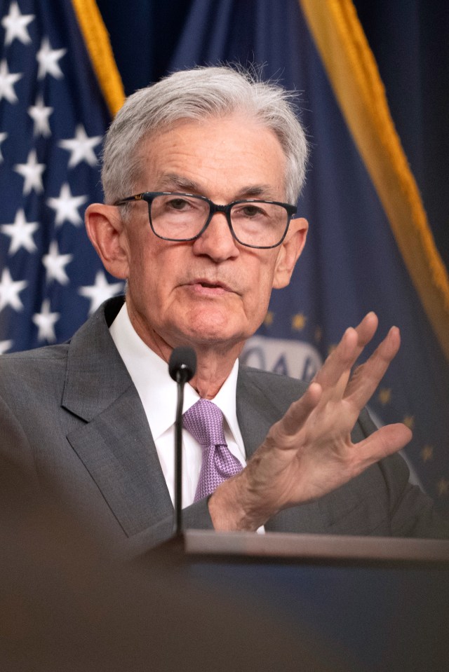 a man in a suit and tie is speaking into a microphone in front of an american flag