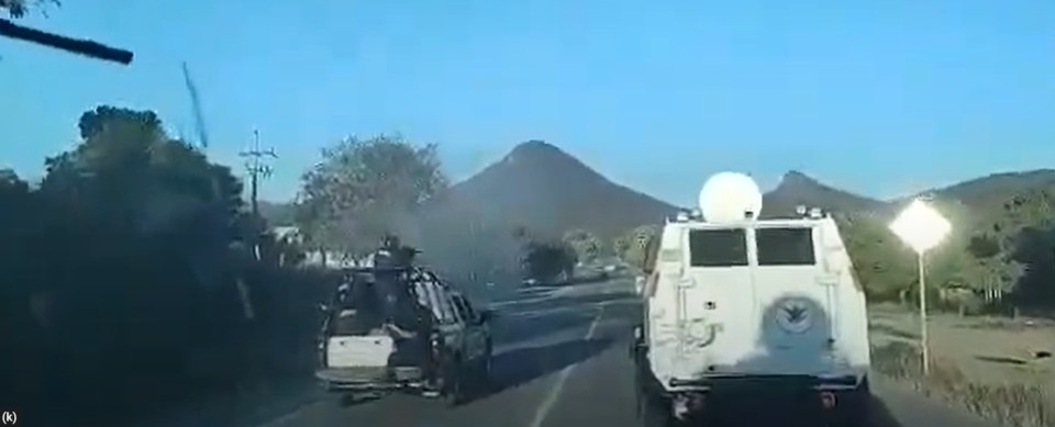 a car is driving down a road next to a military vehicle .