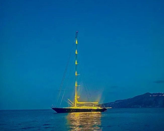 a sailboat is lit up in the middle of the ocean