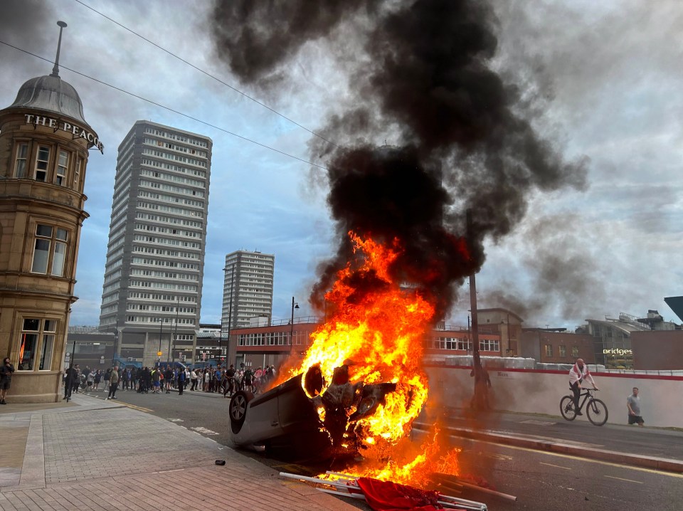 A car was flipped and set alight as crowds of thugs ran riot in the city