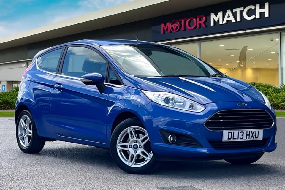 a blue car is parked in front of a motor match store