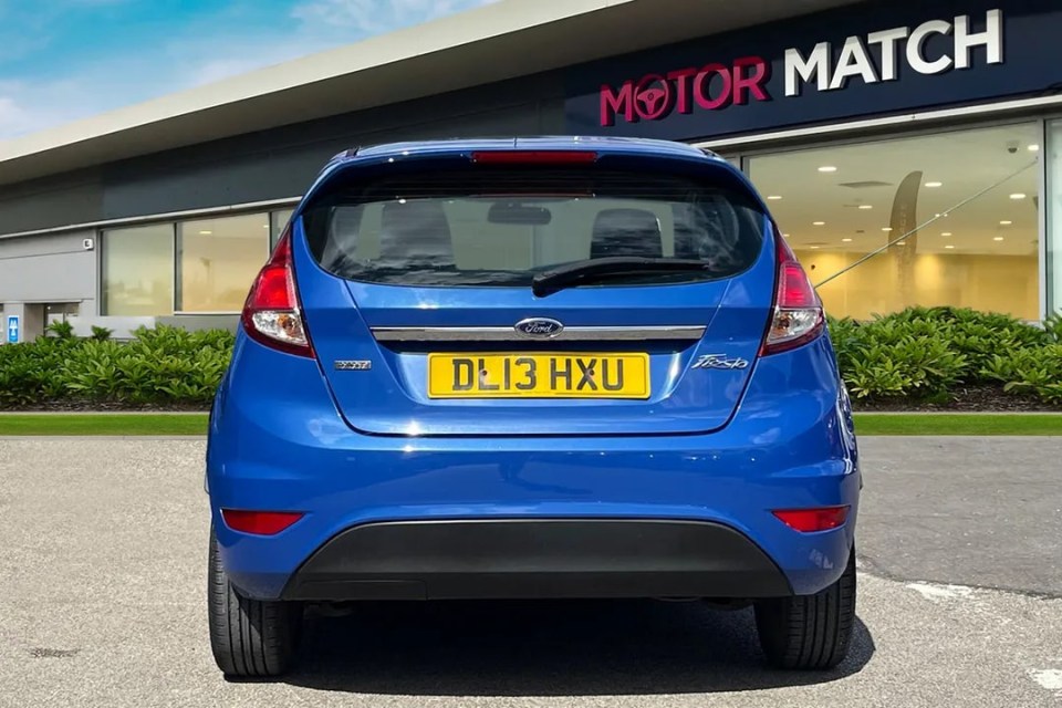 a blue ford car is parked in front of a motor match building