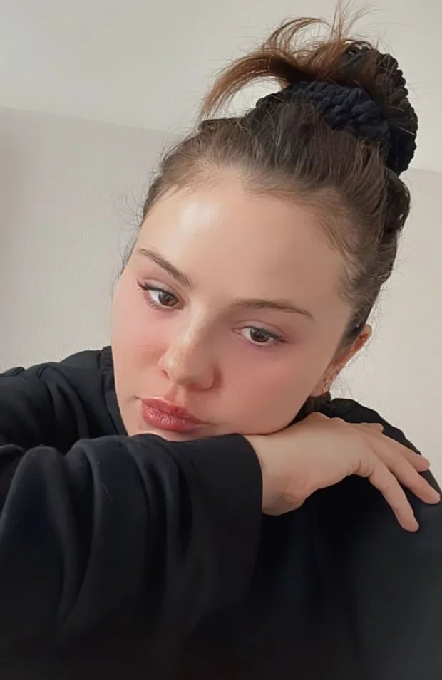 a woman with her hand on her chin is wearing a black shirt