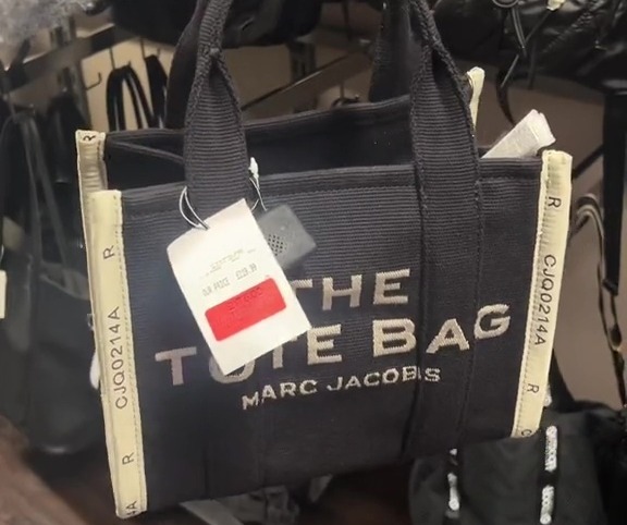 a person is holding a black marc jacobs tote bag