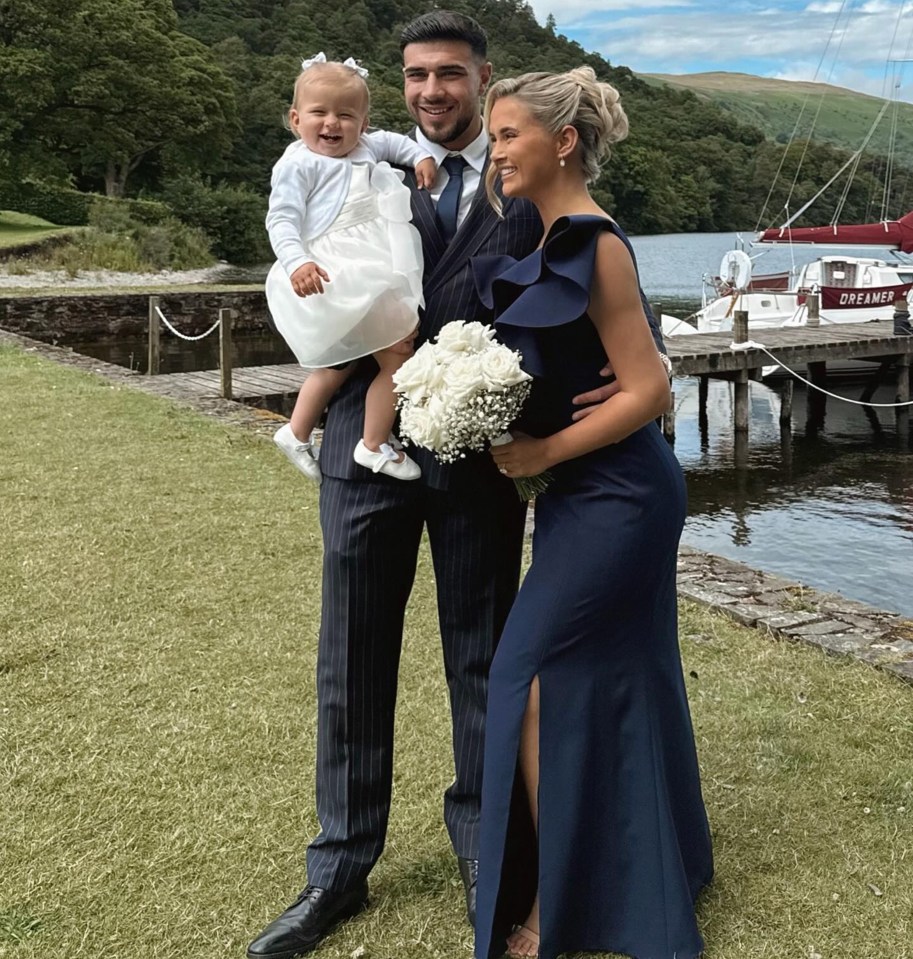 a woman in a blue dress stands next to a man and a little girl