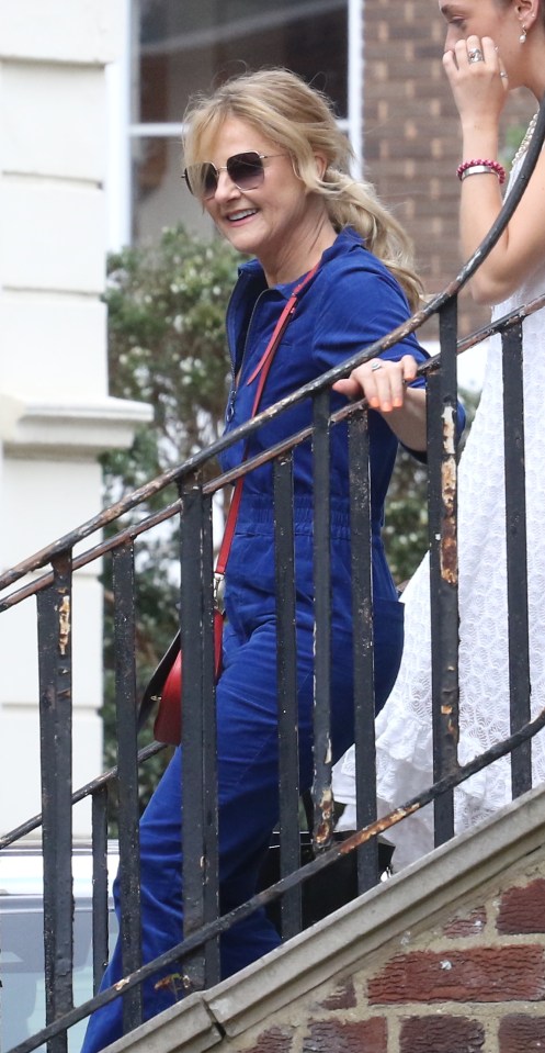 a woman in a blue jumpsuit is walking down a set of stairs