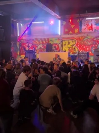 a crowd of people are sitting in front of a dj in a club .