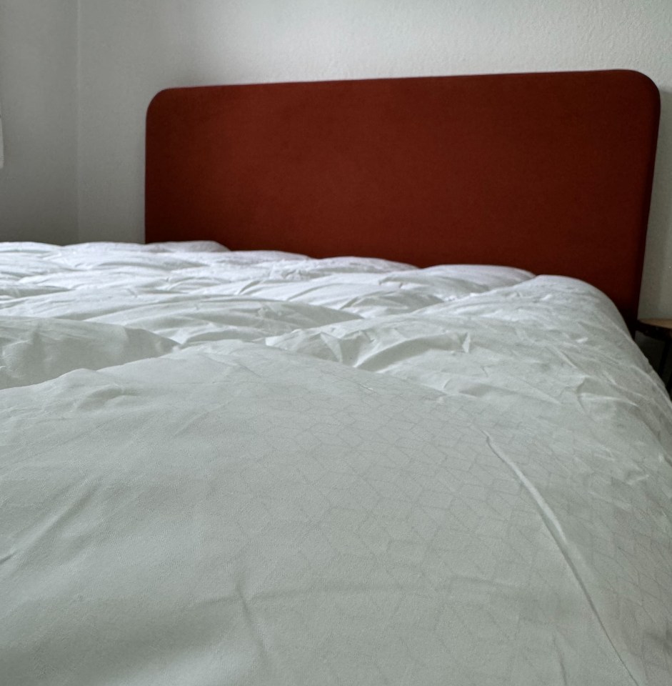 a bed with white sheets and a red headboard