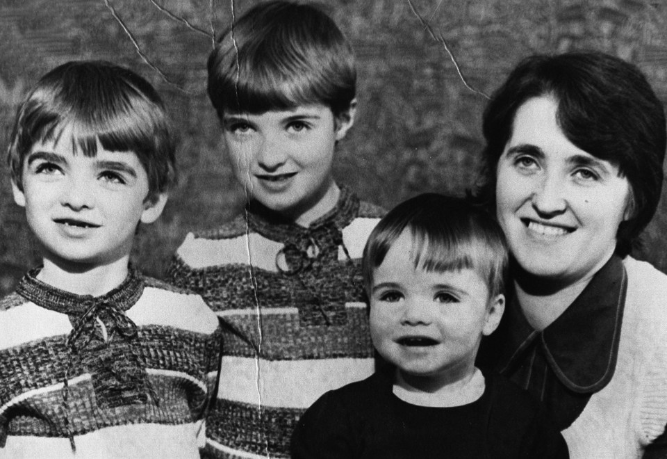 a black and white photo of a woman and three children