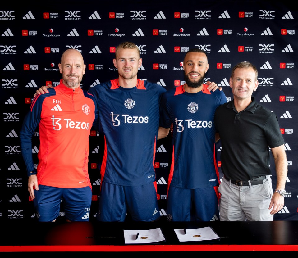 four men standing in front of a manchester united sign