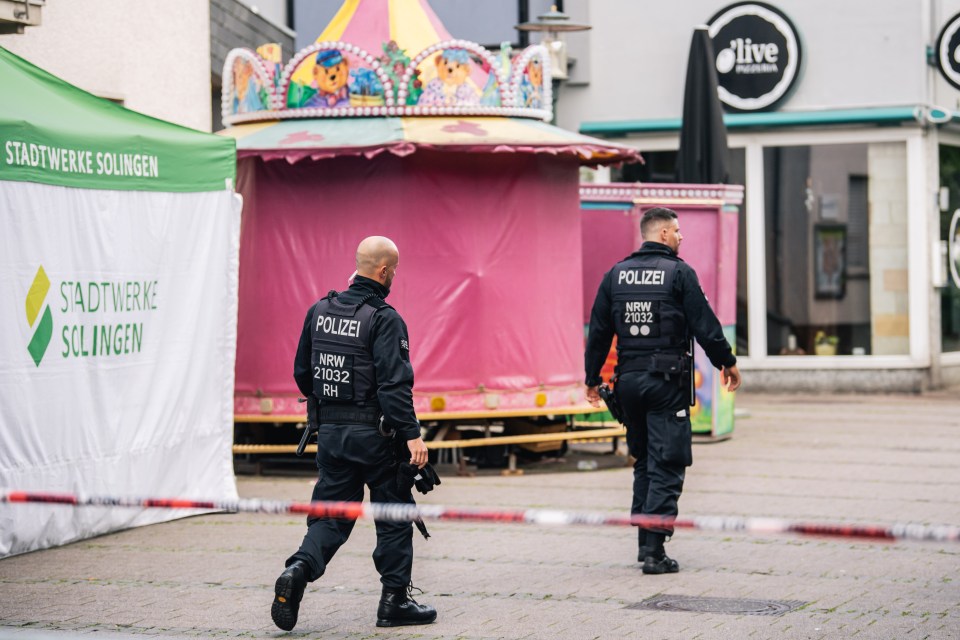 two police officers walking in front of a sign that says stadtwerke solingen