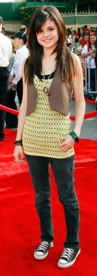 a young girl is standing on a red carpet wearing converse shoes