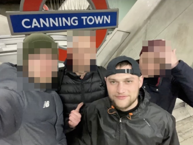 a group of men are posing in front of a canning town sign