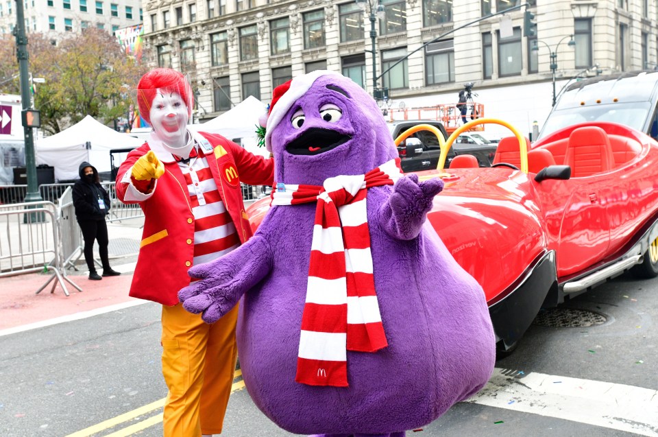 ronald mcdonald and grimace pose for a photo in front of a red car