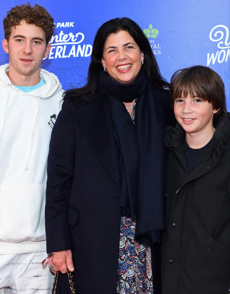 a woman and two boys pose in front of a hyde park winter wonderland sign