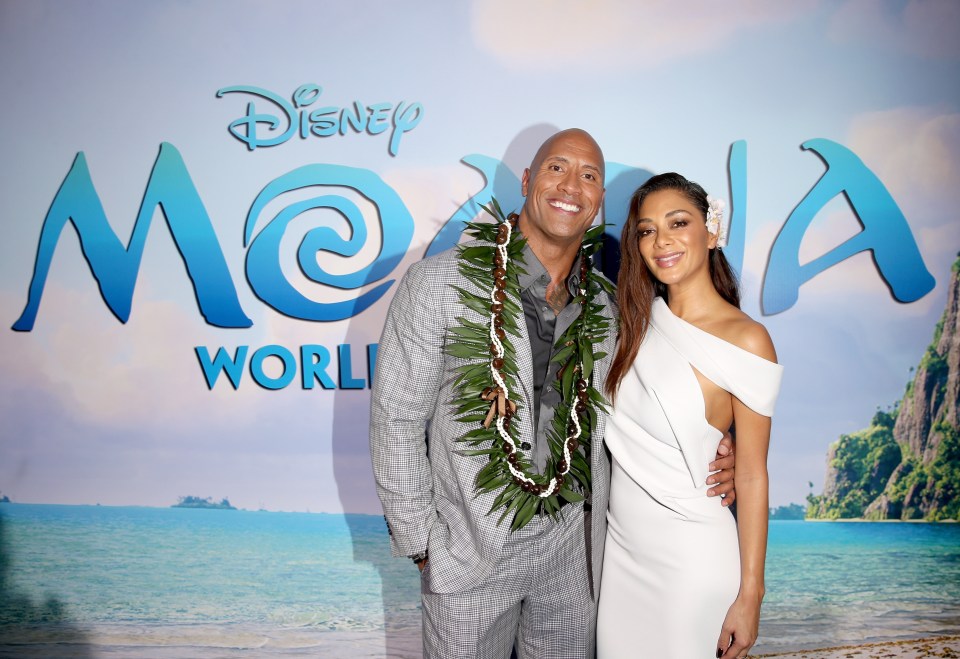 a couple standing in front of a disney world sign