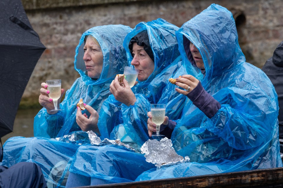 three women wearing blue raincoats are eating and drinking