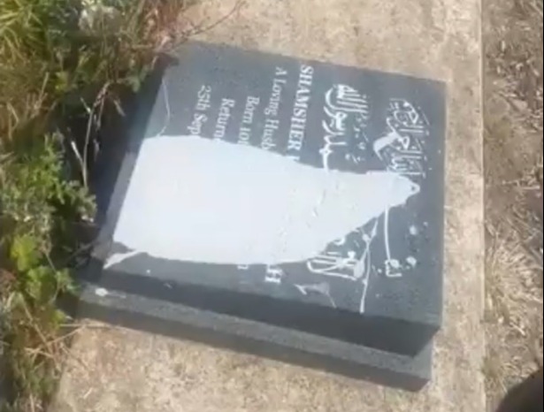 a person is standing next to a gravestone that has been vandalized .