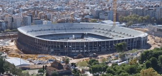 an aerial view of a stadium under construction with a city in the background