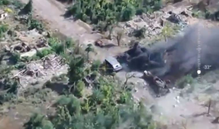 an aerial view of a car driving down a dirt road in the woods .