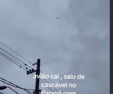 a plane is flying in the sky above a power pole .