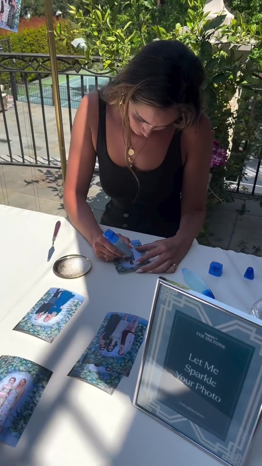 a woman sits at a table with a sign that says let me sparkle your photo