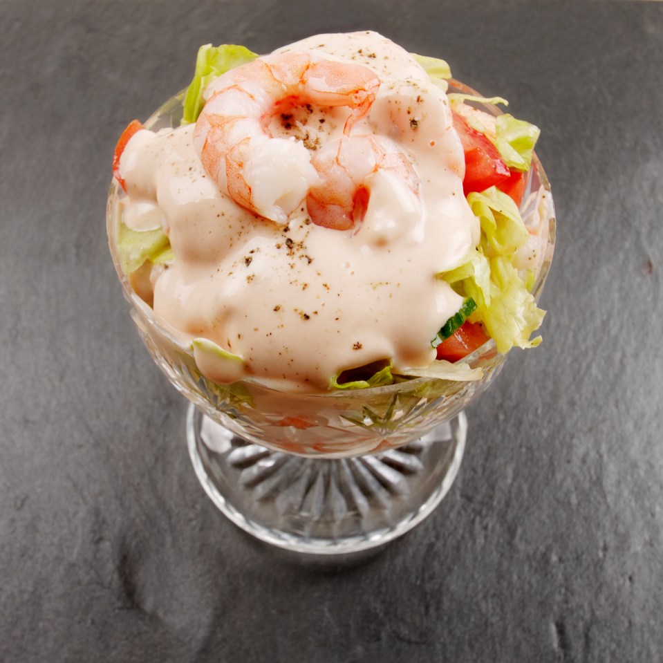 Prawn cocktail in glass dish on slate surface.