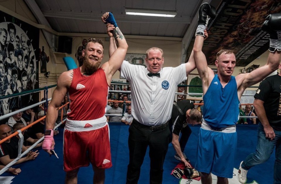 a referee holds up two boxers in a boxing ring