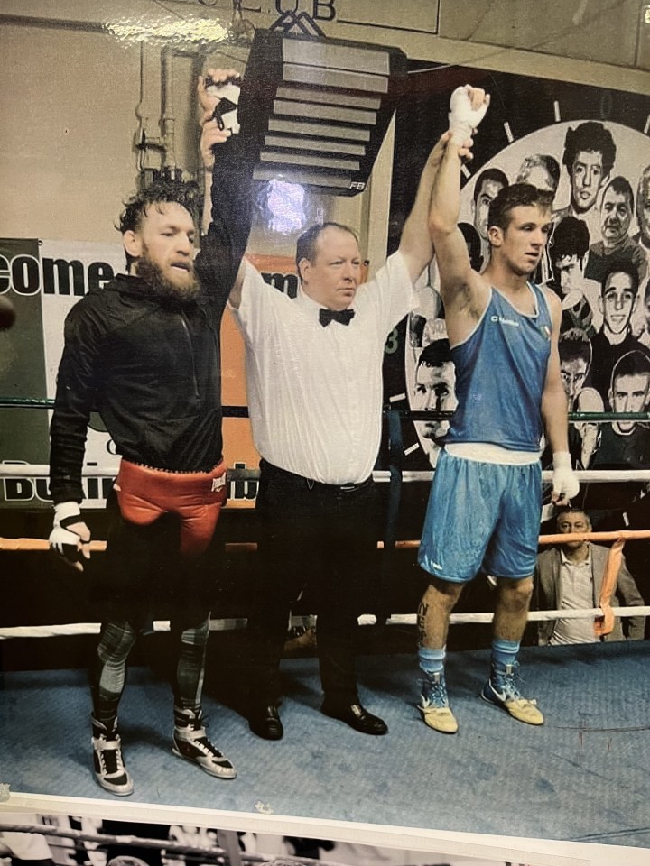 a man in a blue shorts holds up his hand in a boxing ring