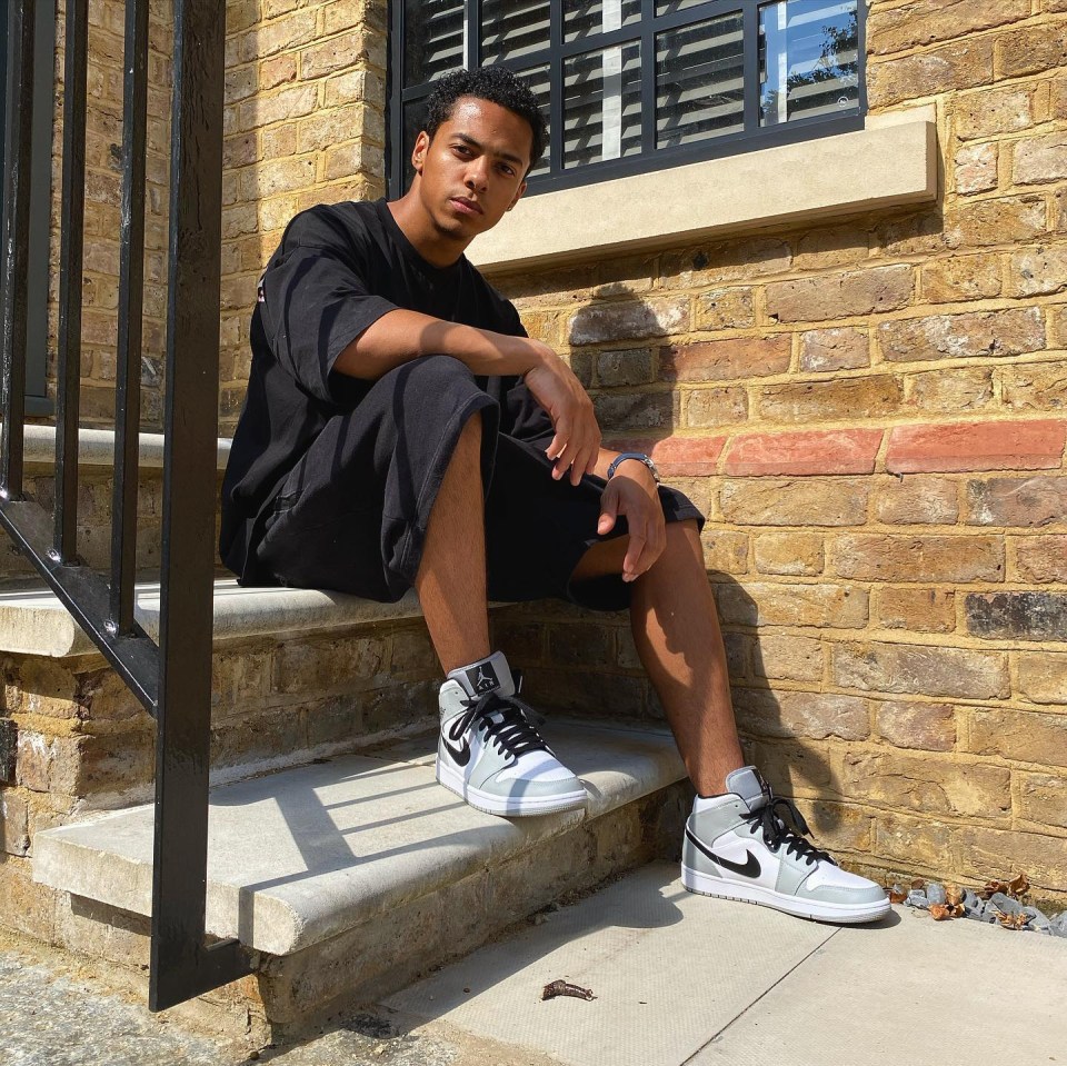 a man sits on a set of stairs wearing a black shirt and black shorts