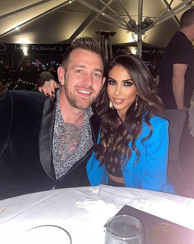 a man and a woman are posing for a picture while sitting at a table .