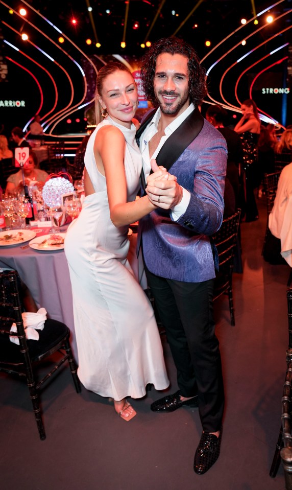 a woman in a white dress is dancing with a man in a blue suit