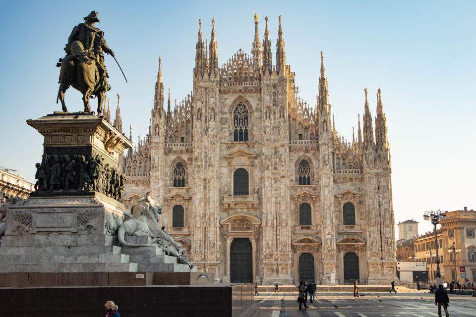 a statue of a man riding a horse in front of a large cathedral with the letters lcg on it