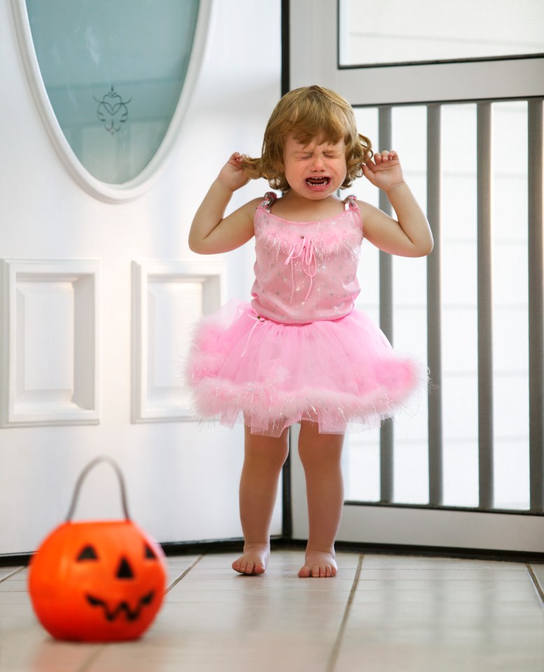 a little girl in a pink tutu is crying in front of a pumpkin