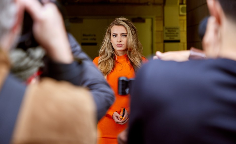 a woman in an orange dress is being photographed by a man