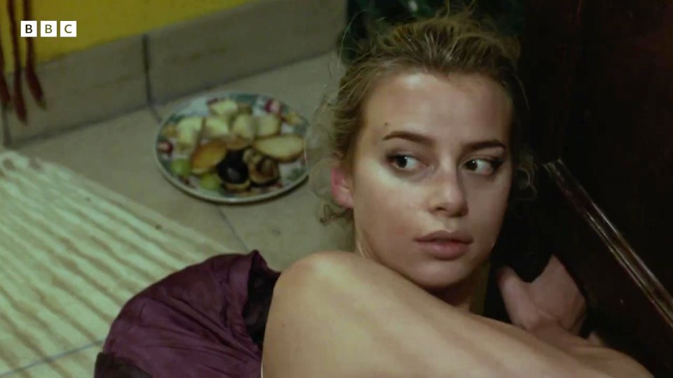 a woman laying on the floor with a plate of food in the background with bbc written on it