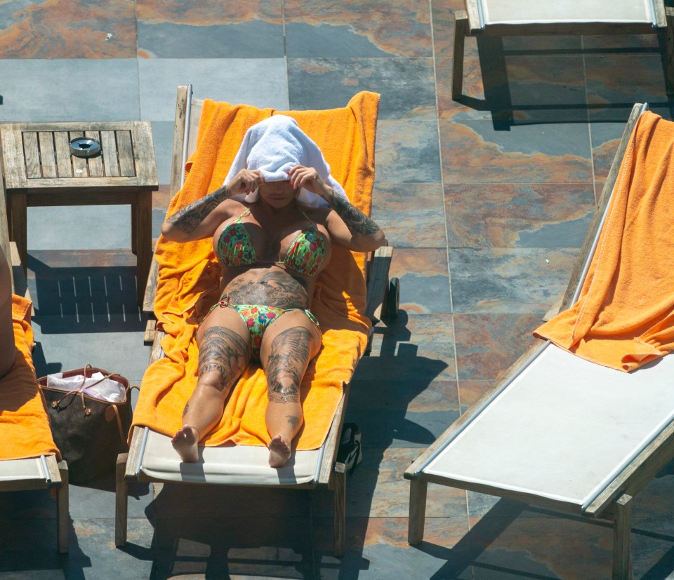 a woman in a bikini is laying on an orange towel