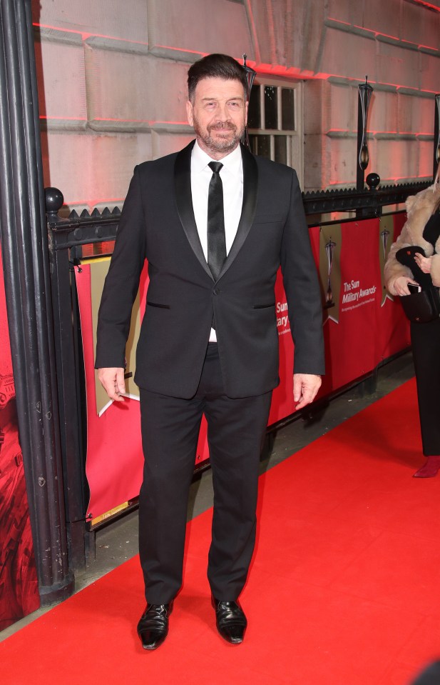 a man in a tuxedo stands on a red carpet in front of a sign that says the sun academy awards