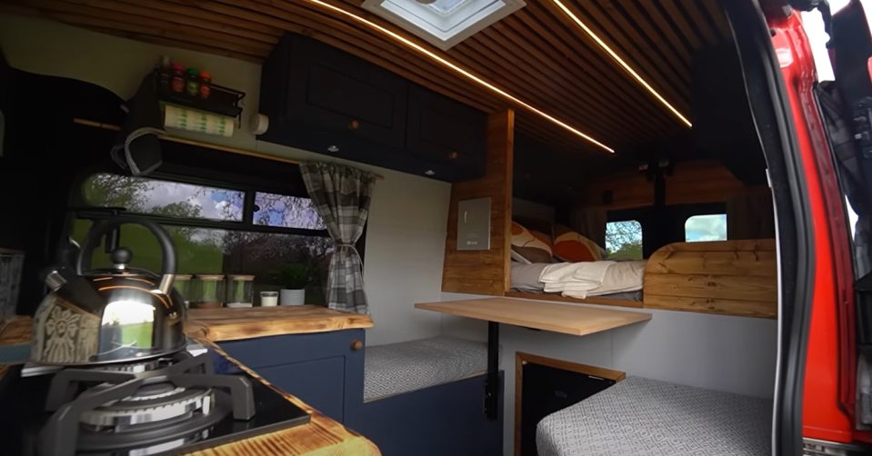 The van has a kitchen, dining area, and bedroom