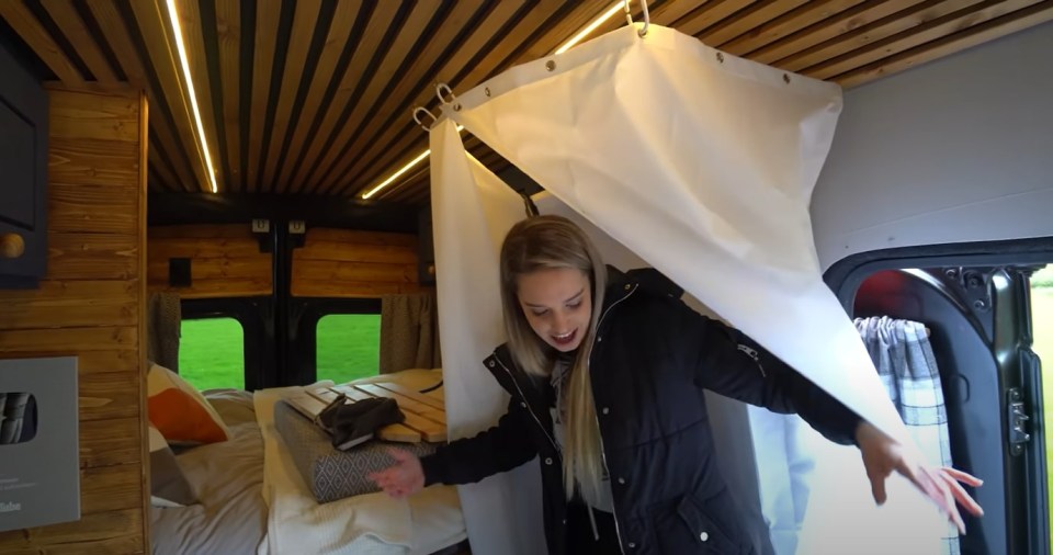 a woman in a black jacket opens the door of a van