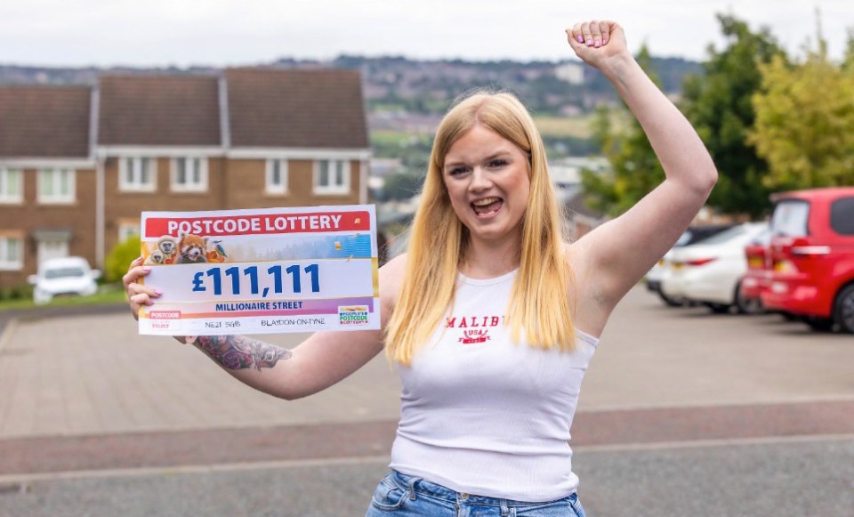 a woman holds up a postcode lottery ticket