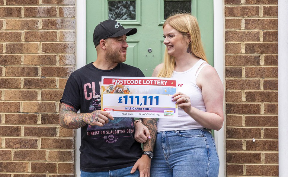 a man and woman holding a postcode lottery ticket