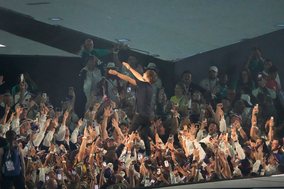 a man stands in front of a crowd of people holding their phones up