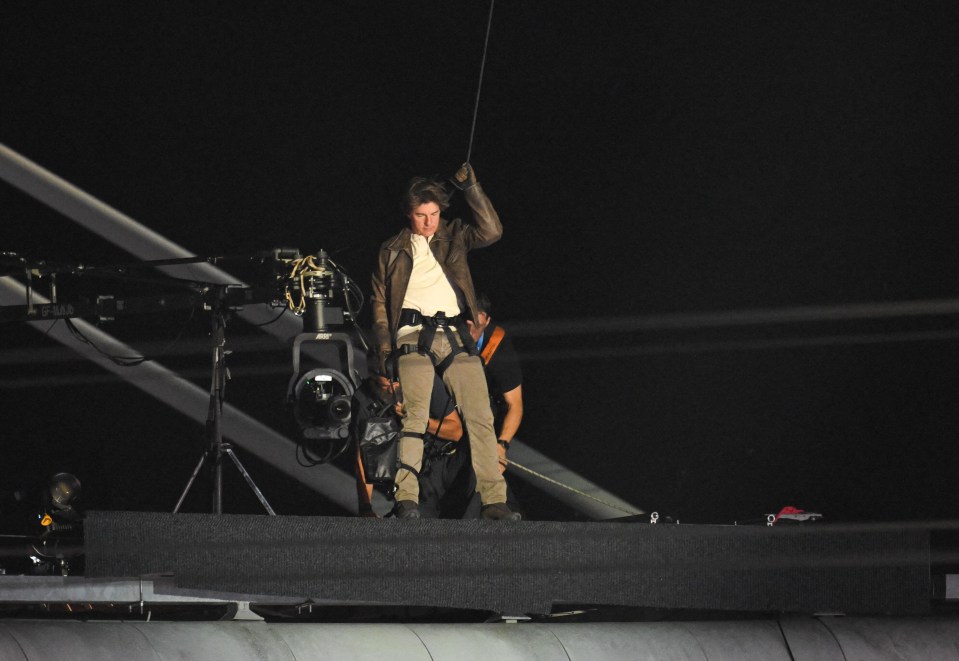 a man in a brown jacket is holding a rope in the dark