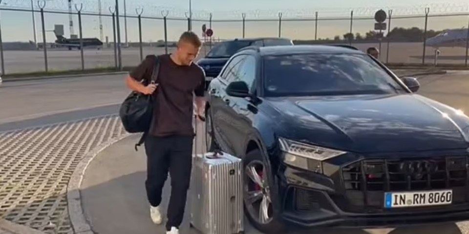 a man is pulling a suitcase next to an audi car .